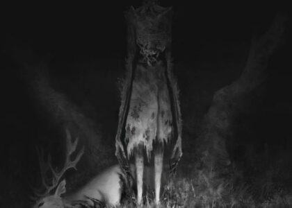 Black and white photo of a monster with glowing eyes in the dark standing Infront of a video camera frame